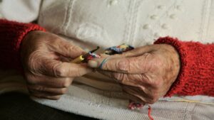 view of older woman with hands crocheting