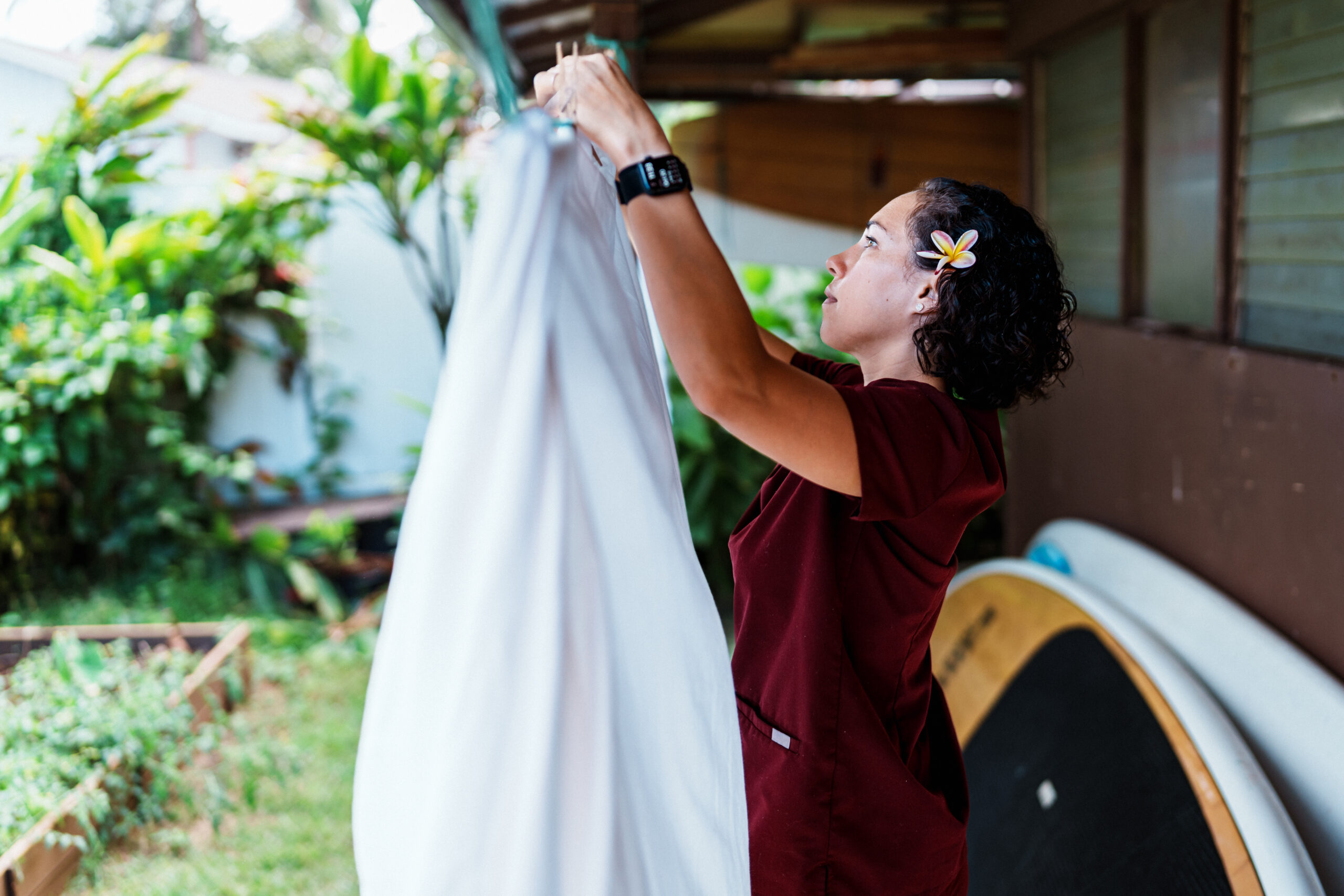 An Eurasian woman of Hawaiian and Chinese descent wearing medical scrubs hangs laundry to dry in the back yard of her home in Hawaii after returning home from work as a nurse.