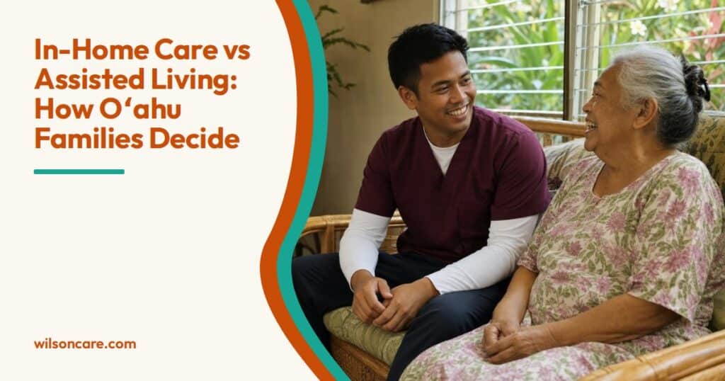 A caregiver in a burgundy top and an older woman in a floral dress laugh together on a rattan sofa in her sunlit living room